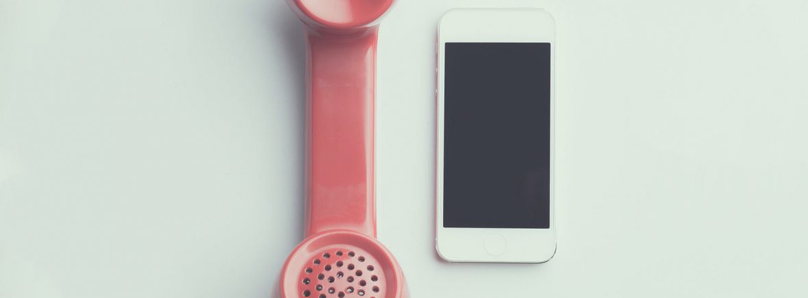 flat lay photography of red anti radiation handset telephone beside iphone